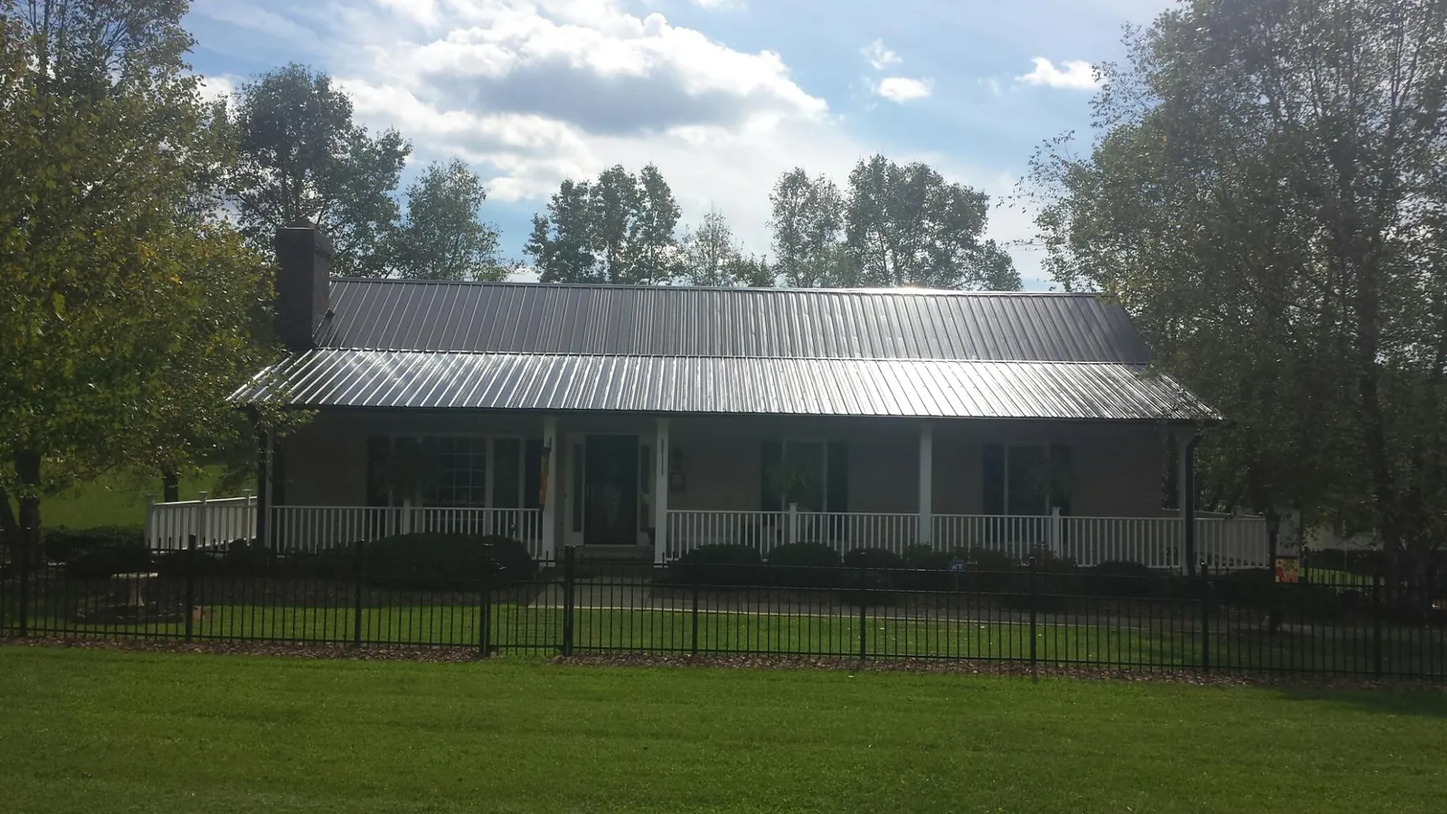 Gray metal roof on a brick ranch with a full width front porch in Boone